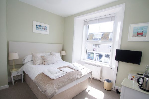 small bright room with double bed and tv